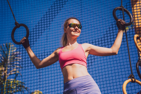 Athletic young woman exercising using gymnastic rings in a training campの写真素材