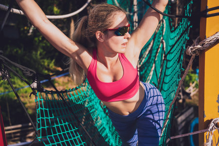 Athletic young woman working out at the rope training camp.