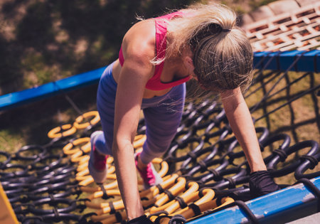 Athletic young woman working out and climbing a ropes at the rope training camp.の写真素材
