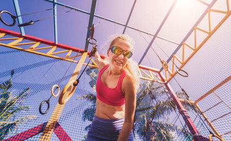 Athletic young woman exercising using gymnastic rings in a training camp