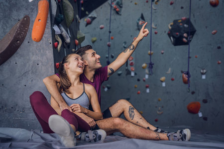 A strong couple of climbers against an artificial wall with colorful grips and ropes.の写真素材