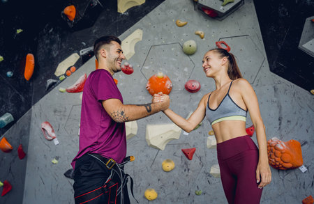 A strong couple of climbers against an artificial wall with colorful grips and ropes.の写真素材