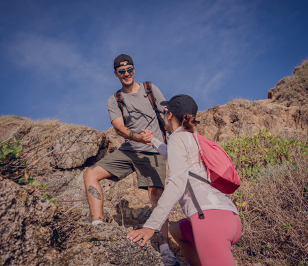 Happy young couple climbs to the top in the mountains near the oceanの写真素材