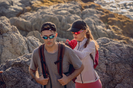 Happy young couple climbs to the top in the mountains near the oceanの写真素材