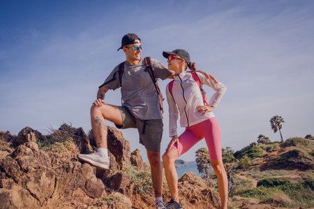 Happy young couple climbs to the top in the mountains near the oceanの写真素材