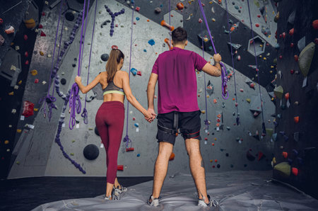A strong couple of climbers against an artificial wall with colorful grips and ropes.の写真素材