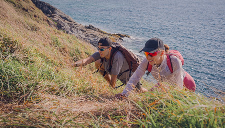 Happy young couple climbs to the top in the mountains near the ocean
