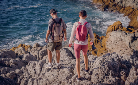 Happy young couple climbs to the top in the mountains near the oceanの写真素材
