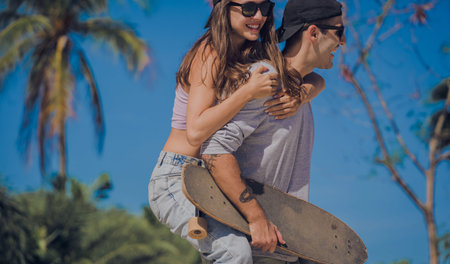 Young happy couple with skateboards enjoy longboarding at the skatepark