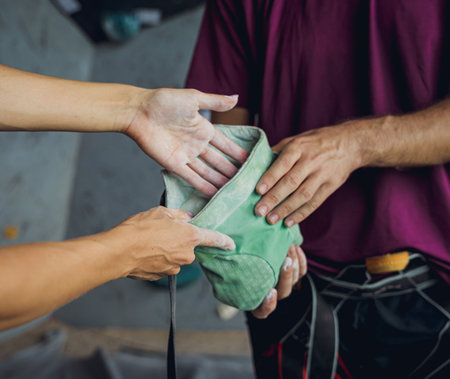 A couple of climbers use talc befor climbing an artificial wall with colorful grips and ropes.の写真素材