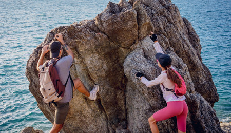 Happy young couple climbs to the top in the mountains near the ocean