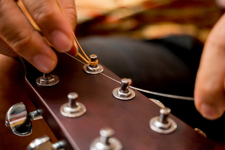 Young musician changing strings on a classical guitar in a guitar shopの写真素材