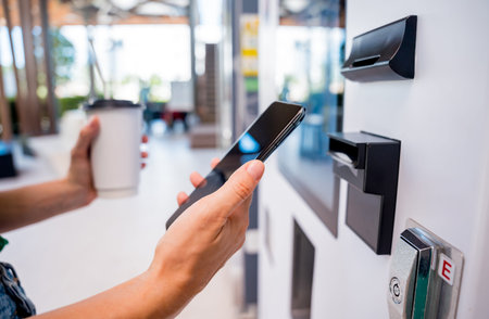 Young woman paying for coffee at vending machine using contactless method of payment