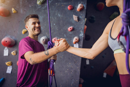 A strong couple of climbers against an artificial wall with colorful grips and ropes.