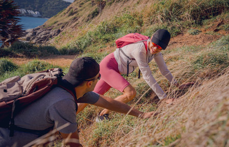 Happy young couple climbs to the top in the mountains near the ocean