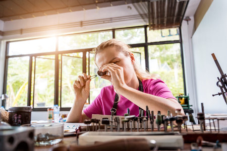 Young female jeweler making jewelry in workshop