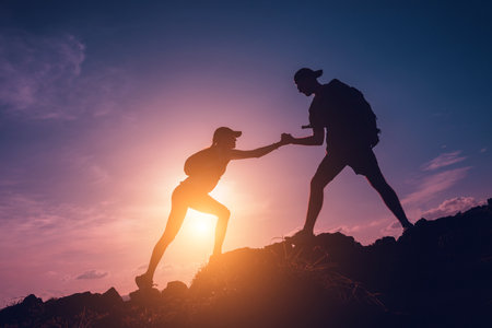 Happy young couple climbs to the top in the mountains near the oceanの写真素材