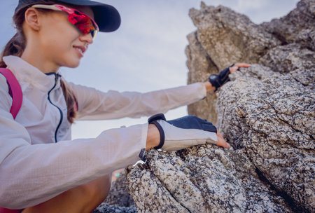 Young woman climbs to the top in the mountains near the ocean
