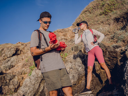Young couple climbs with a rope to the top in the mountains near the oceanの写真素材