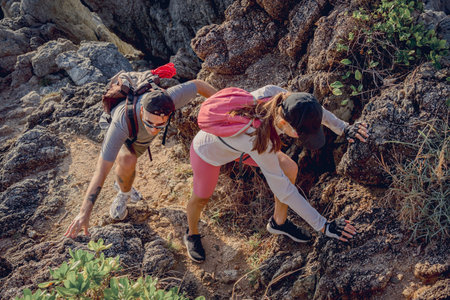 Happy young couple climbs to the top in the mountains near the oceanの写真素材