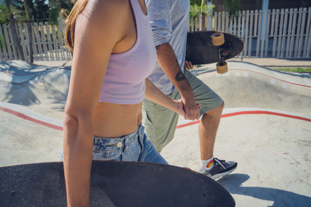 Young happy couple with skateboards enjoy longboarding at the skatepark