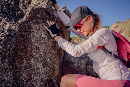 Young woman climbs to the top in the mountains near the oceanの写真素材