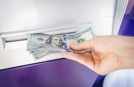 Young woman holding money in her hands after withdrawing the cash at the ATM