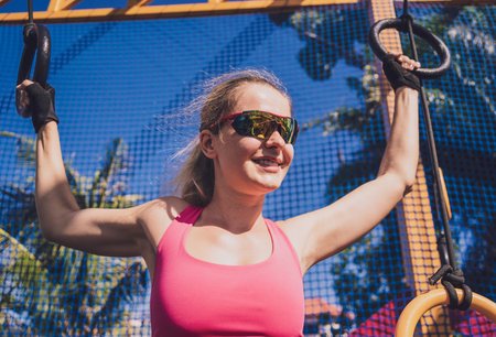 Athletic young woman exercising using gymnastic rings in a training campの写真素材