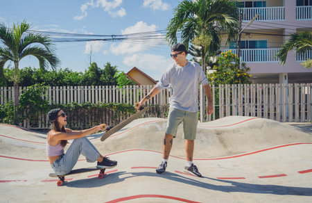 Young happy couple with skateboards enjoy longboarding at the skatepark