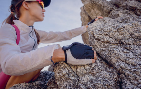 Young woman climbs to the top in the mountains near the ocean