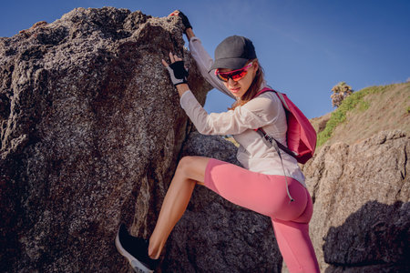 Young woman climbs to the top in the mountains near the oceanの写真素材