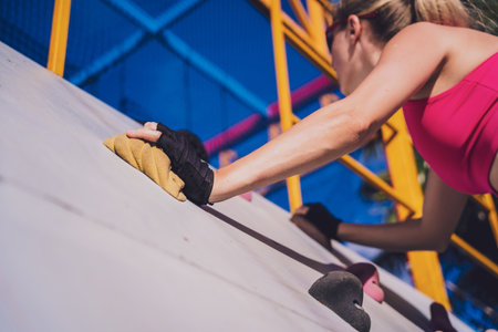 Athletic young woman working out and climbing at the artificial rock in training camp.の写真素材