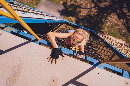 Athletic young woman working out and climbing a ropes at the rope training camp.の写真素材