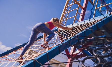 Athletic young woman working out and climbing at the training camp.の写真素材