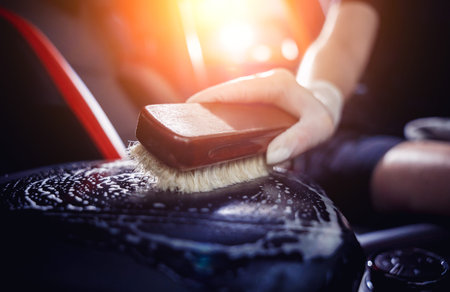 Young woman cleaning the car interior using a special brush with foam