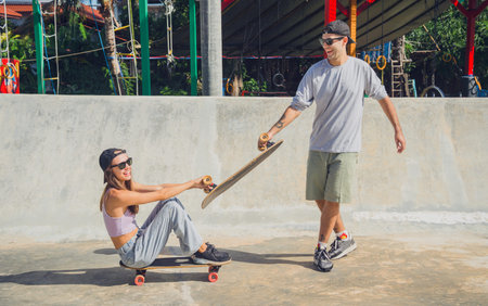 Young happy couple with skateboards enjoy longboarding at the skatepark