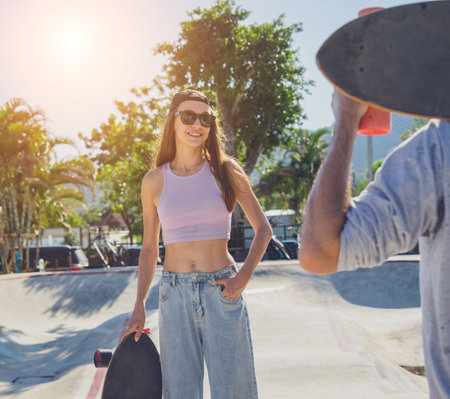 Young happy couple with skateboards enjoy longboarding at the skateparkの写真素材
