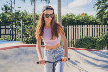 Happy young woman with scooter enjoy riding at the skateparkの写真素材