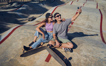 Young happy couple with skateboards taking selfie at the skateparkの写真素材