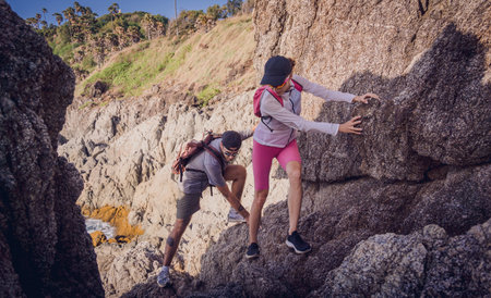 Happy young couple climbs to the top in the mountains near the ocean