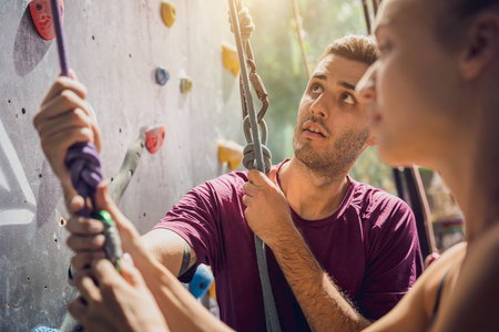 A strong couple of climbers climb an artificial wall with colorful grips and ropes.の写真素材