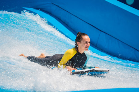 Beautiful young woman surfing on a wave simulator at a water amusement parkの写真素材