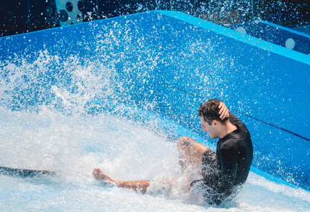 Young man surfing on a wave simulator at a water amusement parkの写真素材