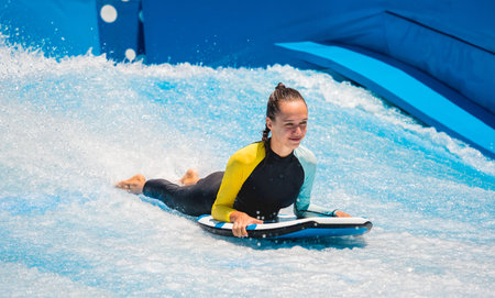 Beautiful young woman surfing on a wave simulator at a water amusement park
