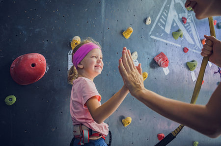 A strong baby climber posing for photographer at artificial wall.