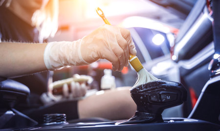 Young woman cleaning the car interior using a special brush with foamの写真素材