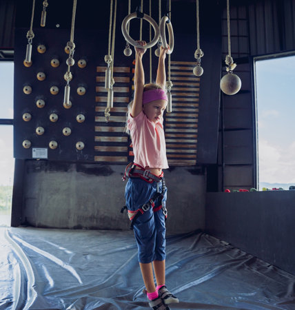A strong baby climber climbs an artificial wall with colorful grips and ropes.の写真素材