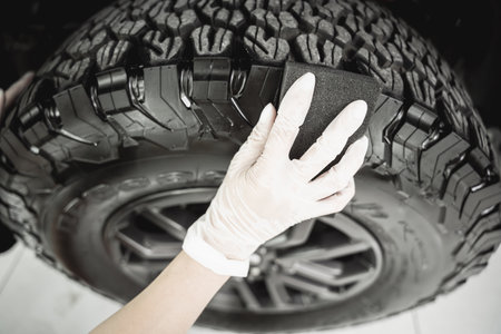 Professional car service worker polishing car tires with black spongeの写真素材