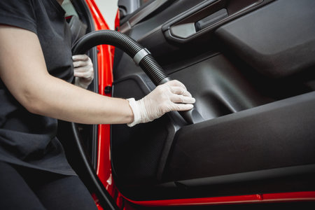 Car detailing worker cleaning and polishing car with microfiber cloth and vacuum.の写真素材
