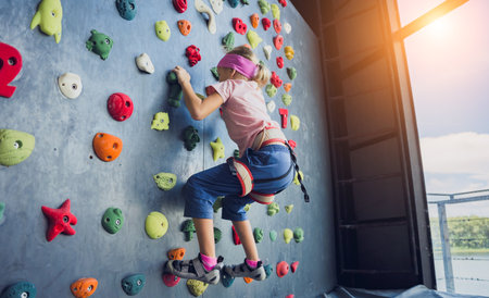 A strong baby climber climbs an artificial wall with colorful grips and ropes.の写真素材